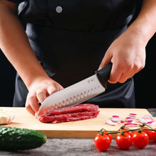 Santoku knife slicing on a wooden board; white blade with black grip handle