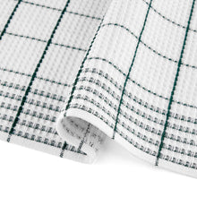 Close-up of white holiday kitchen towel with dark green plaid grid and rolled hem
