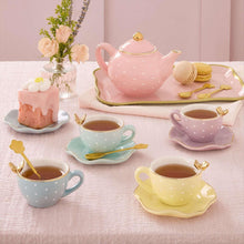 Porcelain tea set arrangement with pink teapot, teacups, saucers, and dessert plate
