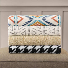 Cozy throw blanket stack with blue, cream, and black geometric patterns