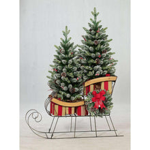 Pre-lit holiday sleigh display with pine topiaries, red bow, and warm light needles