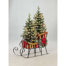 Pre-lit holiday sleigh with pine topiaries, red bow, and lit branches on iron stand