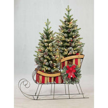 Pre-lit holiday sleigh with two pine topiaries, red bow, and striped runners