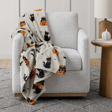 White Halloween cat and jack-o-lantern lounge throw blanket draped over an armchair