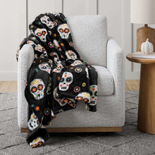 Black Halloween skull and monster lounge throw blanket draped over an armchair