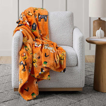 Orange Halloween character lounge throw blanket draped over a light gray armchair