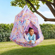 Kids hanging cozy pod with heart-pattern fabric outdoors in a yard