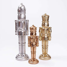 Nutcracker figurines set: silver, bronze, and gold nutcrackers standing on bases