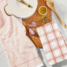 Kitchen towel set display with pale peach striped and plaid towels on a countertop