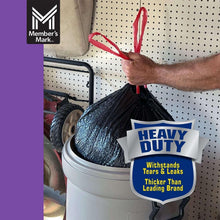 Person filling a large gray bin with a black heavy-duty trash bag; heavy duty label
