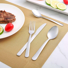 Stainless steel dinner forks on placemat, three forks with four tines each