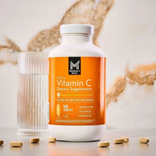 Vitamin C dietary supplement bottle with orange label and scattered oval tablets