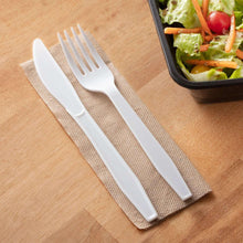 White plastic knives set, three utensils on a woven placemat.