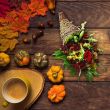 Cornucopia floral arrangement with red roses, green leaves, and small mixed flowers.
