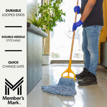 Blue blended mop head with purple trim near yellow mop handle held by a gloved hand.