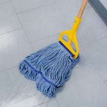 Blue mop head with purple trim on tile floor, attached to yellow handle base.