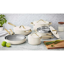 Cream ceramic cookware set with gold handles, including skillet, pots, and lids