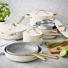 Cream ceramic cookware set with gold handles, including skillet and covered pots