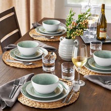 Green artisan dinnerware set with bowls and plates in layered stacks, speckled glaze