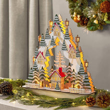 Pre-lit village scene decoration with glowing houses, evergreen trees, and lanterns on base