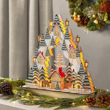 Pre-lit village holiday scene decoration with lit houses, trees, and lanterns on base