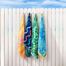 Fashion beach towels hanging on fence, blue, green, and yellow patterned fabric
