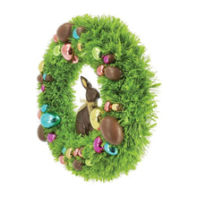 Green tinsel wreath with chocolate bunny ornament at center and colorful baubles