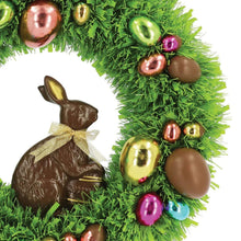 Close-up green tinsel wreath edge with chocolate bunny ornament and shiny baubles