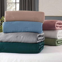 Comforter set with pillow shams stacked in blue, grey, and green tones