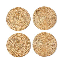 Four round woven water hyacinth placemats in natural tan, flat on a white surface.