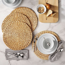 Round natural woven placemat set, with two mats laid flat and gray napkins nearby.