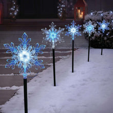 Snowflake LED pathway lights with glowing blue snowflake toppers on black stakes