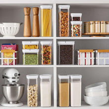 Clear pantry storage containers with flip-lock lids holding pasta, grains, and spices