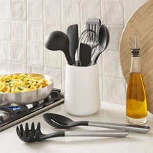 Black silicone cooking utensils with stainless handles, in a white utensil holder