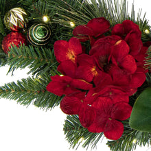 Pre-lit Christmas garland close-up with pine tips, red poinsettia blooms, and gold lights