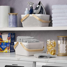 White perforated storage basket with curved light wood handles for organizing.