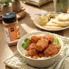 Butter chicken curry over rice in a bowl with Member’s Mark seasoning bottle nearby
