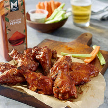 Cayenne pepper seasoning bottle beside cooked chicken wings on parchment