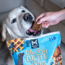 Dog eating a chicken waffle bite held from a Member's Mark treat bag