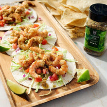 Cilantro lime seasoning jar next to shrimp tacos on a cutting board