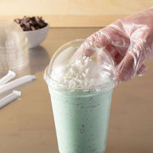 Clear plastic dome lid with straw slot being placed on a cup