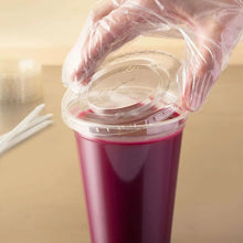 Clear flat plastic lid with straw slot being placed on a drink cup
