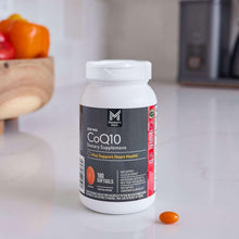 CoQ10 softgels bottle with orange softgel capsule on a countertop