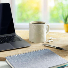 Coffee mug on a desk with laptop and notebook nearby