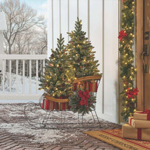 Pre-lit holiday sleigh with two pine topiaries, red bow, and striped base