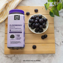 Elderberry gummies bottle with bowl of dark elderberry gummies on a wooden tray