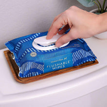 Flushable wipes pouch with wipe pulled out, blue-and-white stripes and dots