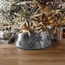 Galvanized metal tree collar with snowflake design, holding a lit tree skirt