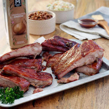Seasoning bottle beside cooked pork spare ribs on a serving tray