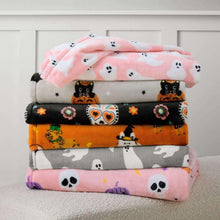 Stack of Halloween lounge throw blankets with gray, orange, black, and pink prints